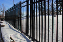 Snow Covered Ledge, Framed By A Black Rod Iron Fence, And Blue Sky.