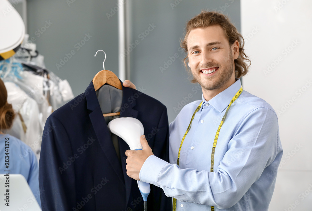 Worker of modern dry-cleaner's steaming clothes