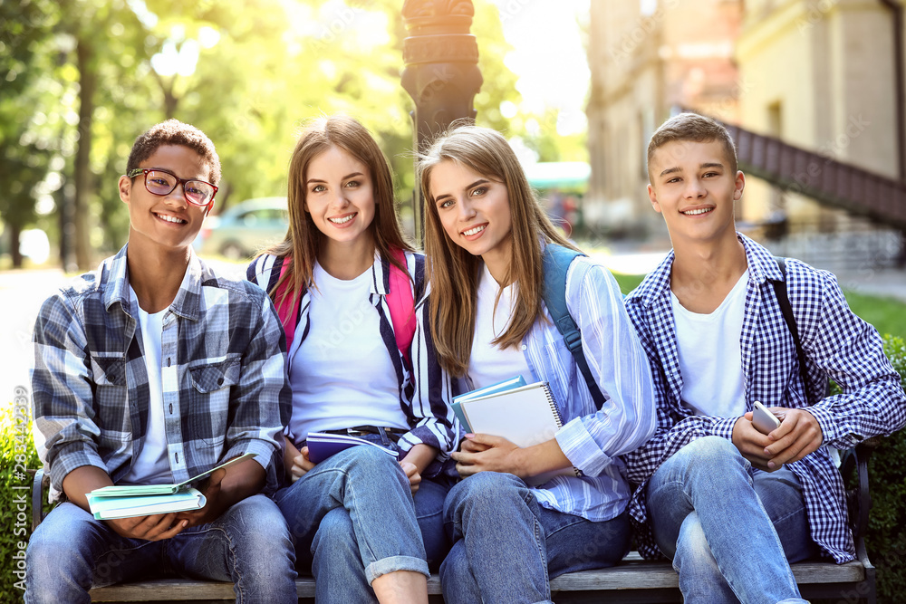 Young students sitting on bench outdoors