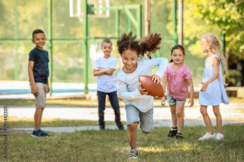 Fotomural Cute little children playing with rugby ball in park