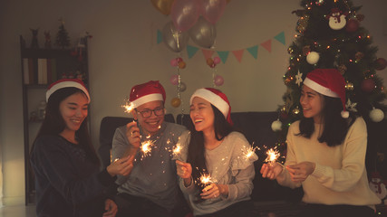 Group of asian young people celebrating Christmas party by sparkle firework