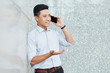 © DragonImages - Portrait of young Asian entrepreneur gesturing when talking on phone and explaining information to client