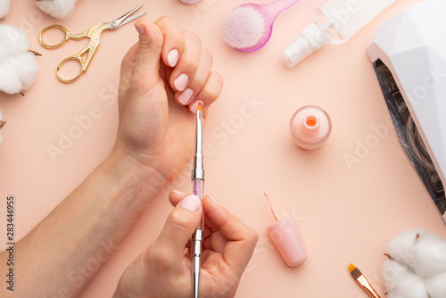 nail-care-beautiful-women-hands-making-nails-painted-with-pink-gentle-nail-polish-on-a-pink-background-women-s-hands-near-a-set-of-professional-manicure-tools-beauty-care