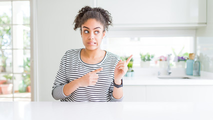 Sticker - Beautiful african american woman with afro hair wearing casual striped sweater Pointing aside worried and nervous with both hands, concerned and surprised expression