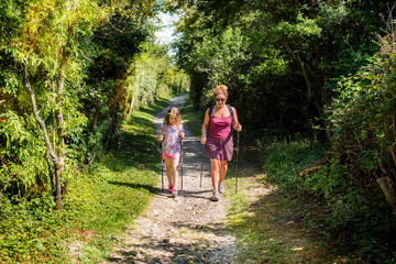 Wall Mural - beautiful girl and her mom doing nordic walking with sticks in the countryside