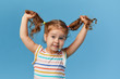 © oes - Portrait of surprised smiling cute little toddler girl. child standing isolated over blue background. Looking at camera and laughs