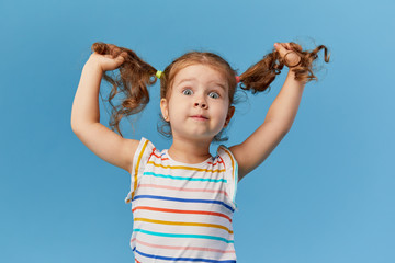 portrait of surprised smiling cute little toddler girl. child standing isolated over blue background
