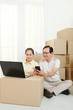 © DragonImages - Smiling senior Vietnamese couple searching for best movers company online