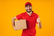 Portrait of attractive delivery man in red uniform showing thumb up and holding packaging box