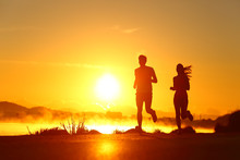 Couple Shilouette Running At Sunrise On The Beach