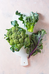 Wall Mural - Broccoli and Kale leaves on a marble board. Healthy fresh green vegetables. Top view.