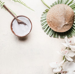 Wall Mural - Coconut oil or butter in wooden bowl with spoon and whole coconut on tropical leaves and flowers, top view . Copy space . Healthy plant based fat source. Vegan food and cosmetic