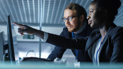 Wall Mural - african american female scientist works on a computer and having discussion with caucasian male coll
