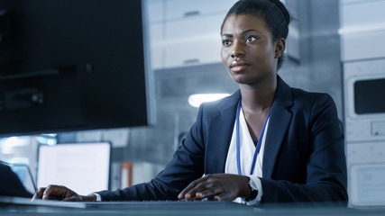 Wall Mural - african-american female scientist working on a computer with her colleagues at research center.