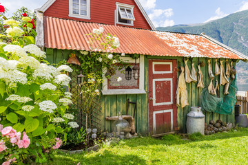 Traditional old green wooden house with stockfish and a fishing net in Aurlandsvangen at the coast of Aurlandsfjord, branche of Sognefjord in Norway