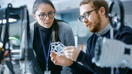 Wall Mural - young talented male and female engineers in a modern laboratory discussing prototype built with the 
