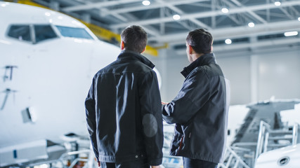 Wall Mural - Aircraft Maintenance Workers having Conversation. Holding and using Tablet.