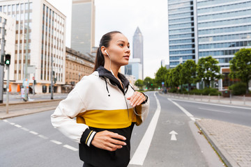 Poster - Photo of athletic beautiful woman listening music with earphones and running on city street