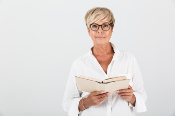 Portrait of confidence middle-aged woman wearing eyeglasses holding book and looking at camera