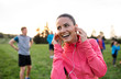 © Halfpoint - A young woman with group of people doing exercise in nature, resting.
