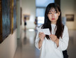 © JackF - Chinese woman standing with guide-book near painting in baguette
