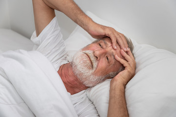 Wall Mural - Senior elderly man on bed eye open sleeplessness and worry, with white blanket in bedroom