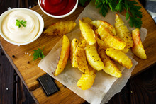 Homemade Tasty French Fries On Cutting Board With Mayonnaise And With Ketchup, On Wooden Table Background.