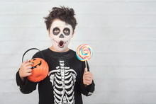 Happy Halloween.funny Child In A Skeleton Costume Eating Lollipop In Halloween