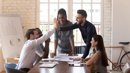 Poster - Motivated male colleagues give high five at multiracial group meeting