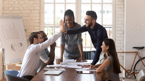 Cuadros en Lienzo Motivated male colleagues give high five at multiracial group meeting