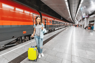 Girl traveler with Luggage and suitcase holding a train or subway ticket with qr-code