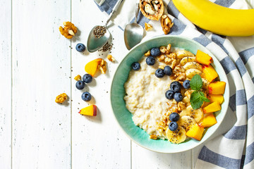 Sticker - Healthy food for Breakfast, vegetarian, vegan, alkiline diet food concept. Oatmeal porridge with chia, banana and blueberry on fruits and nuts on a white wooden table. Top view flat lay.