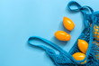 Leinwandbild Motiv Fresh yellow tomatoes in a cotton string bag on a blue background. Flat lay, top view, copy space