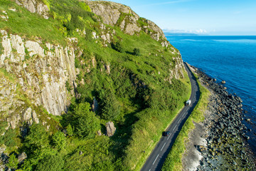 Wall Mural - Northern Ireland, UK. Antrim Coast Road a.k.a Causeway Coastal Route near Ballygalley Head and resort. One of the most scenic coastal roads in Europe. Aerial view in the morning in sunrise light