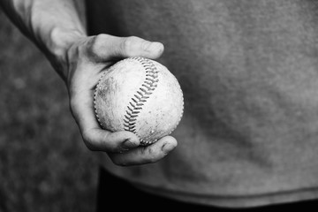 Canvas Print - Old game ball in hand of baseball player closeup, black and white sport concept.