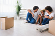 © lordn - Young Happy African-american Family Unpacking after Move. Sitting on a Floor Resting at Their New Home.
