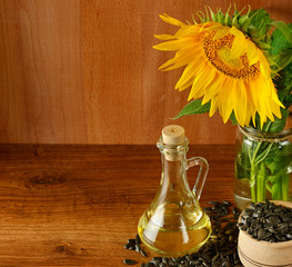 Wall Mural - Seeds, oil and sunflowers flower on wooden background. Free space for text.