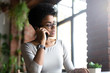 © fizkes - Pensive biracial female busy talking on cellphone at work