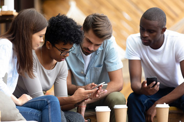 Diverse young people busy using smartphones together