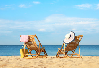 Canvas Print - Empty wooden sunbeds and beach accessories on sandy shore