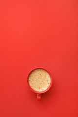 Cup of coffee on red background, top view. Space for text