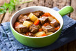 © Ildi - Fresh homemade beef stew with carrot and potatoes served in green bowl (Selective Focus, Focus one third into the stew)