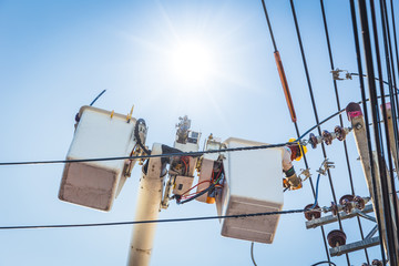 Electricians engineer on crane lifting platform to repair public power line