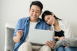 © nuiiko - Happy Asian couple shopping online with holding credit card and laptop and sitting at home together, lifestyle