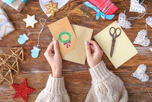 Woman With Envelope And Handmade Christmas Card At Wooden Table