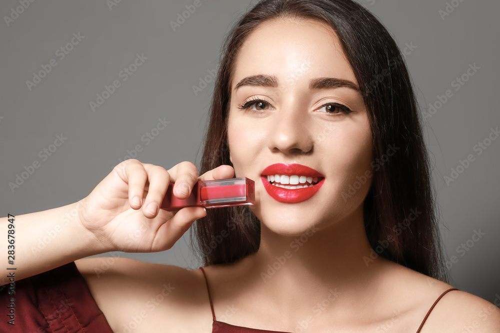 Beautiful young woman with bright lipstick on grey background