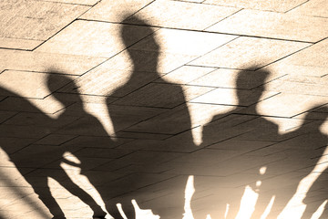 People, shadows and silhouettes of people on sidewalk, pavement in morning lights, as Background or texture, concept picture