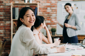 confident beautiful female worker looking at camera posing and smiling. pretty women partners sitting and having discussion during colleagues corporate meeting. group coworkers negotiations in office