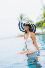 Portrait beautiful young asian woman smile happy relax around swimming pool in hotel resort