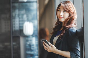 Young attractive asian business woman using mobile phone in  working place.